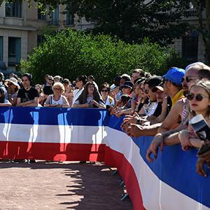 Spectateurs du défilé militaire derrière une banderole tricolores